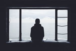 person sitting in a window looking at the sea