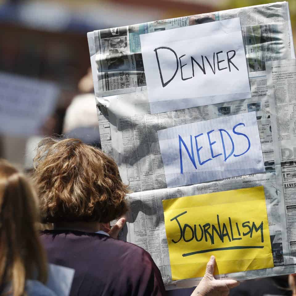 An employee of The Denver Post holds up a sign during a rally against the paper's ownership group, Alden Global Capital, Tuesday, May 8, 2018, outside the paper's office and printing plant in north Denver. (AP Photo/David Zalubowski)