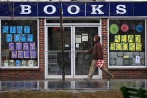 man walks by bookstore with signs