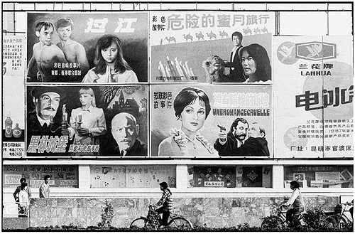 Cyclists and pedestrians under a wall of billboard posters featuring Chinese films and Western films with Chinese titles in 1988