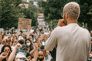 Back shot of an activist speaking in front of a gathered crowd of Black Lives Matter demonstrators
