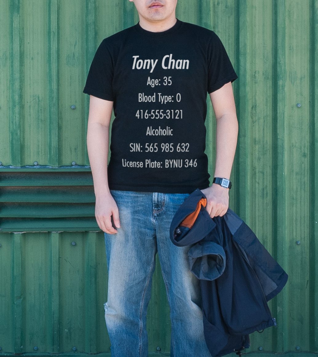 A man wears a t-shirt with all his personal information printed on the front.