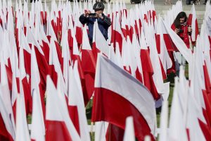a man takes a photograph amid a field of Polish flags