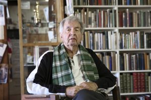 Larry McMurtry seated in front of books