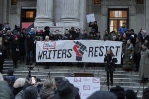 PEN America CEO Suzanne Nossel speaking in front of a group of people behind a “Writers Resist” sign