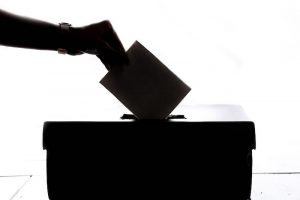 hand placing vote into a ballot box