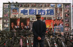 A security guard looks at a billboard full of movie posters outside a Beijing theatre Friday, April 25, 1997. Chinese can now watch a wide selection of movies, ranging from locally produced communist propaganda films to Hollywood blockbusters.