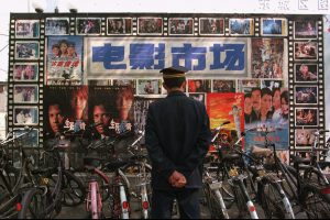 A security guard looks at a billboard full of movie posters outside a Beijing theatre Friday, April 25, 1997. Chinese can now watch a wide selection of movies, ranging from locally produced communist propaganda films to Hollywood blockbusters.