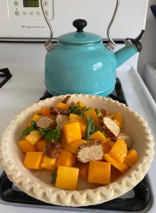 Light blue kettle next to open pie with vegetables in it