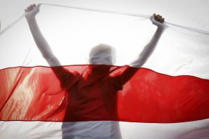 Silhouette of a demonstrator behind a Belarusian national flag
