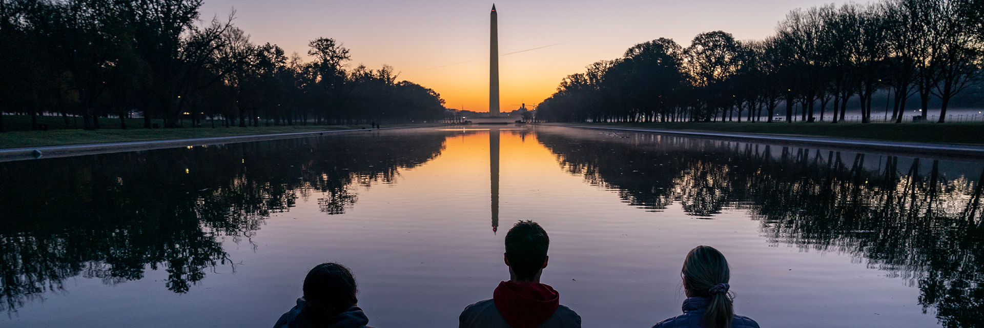 Washington Monument with three people in foreground