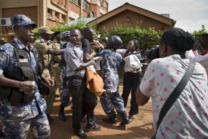 On the left: media and members of Uganda's Human Rights Network for Journalists struggling with police; on the right: person photographing the clashes