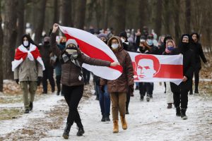 protesters in face masks carrying old Belarusian national flags
