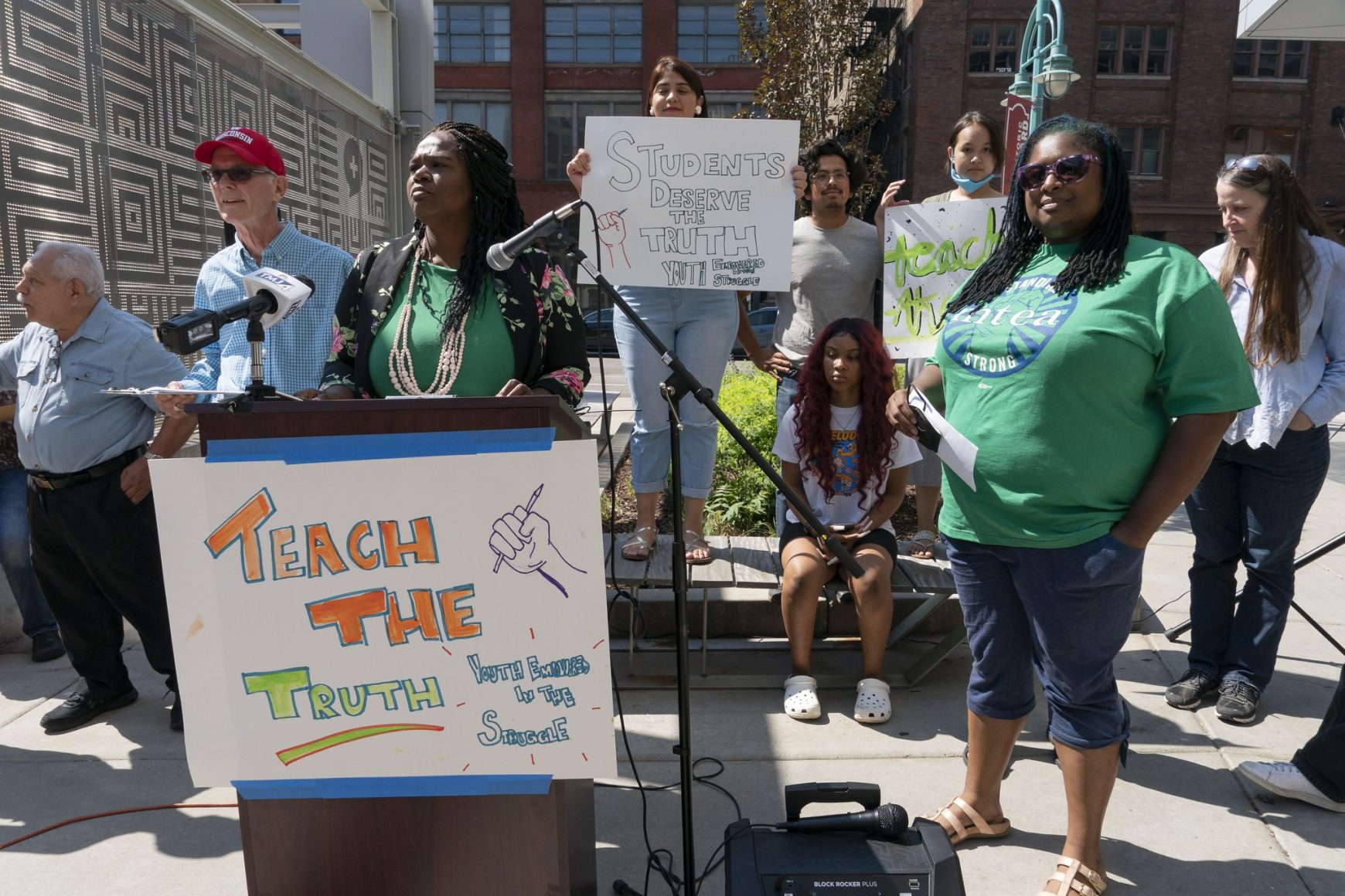 Organized students and teachers at the “Teach the Truth” Rally, some holding signs and one behind a podium