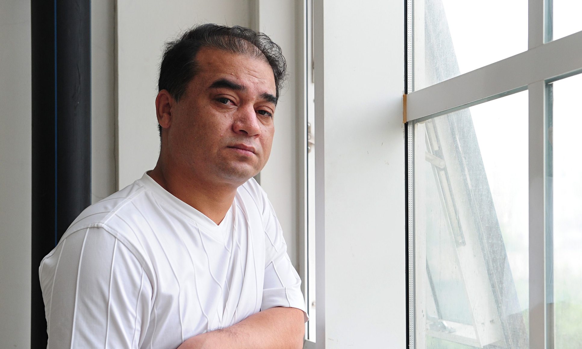 Ilham Tohti leans on a windowsill