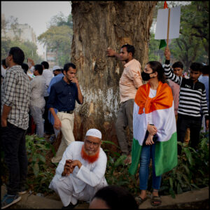 People stand by a tree woman with Indian flag wrapped around her