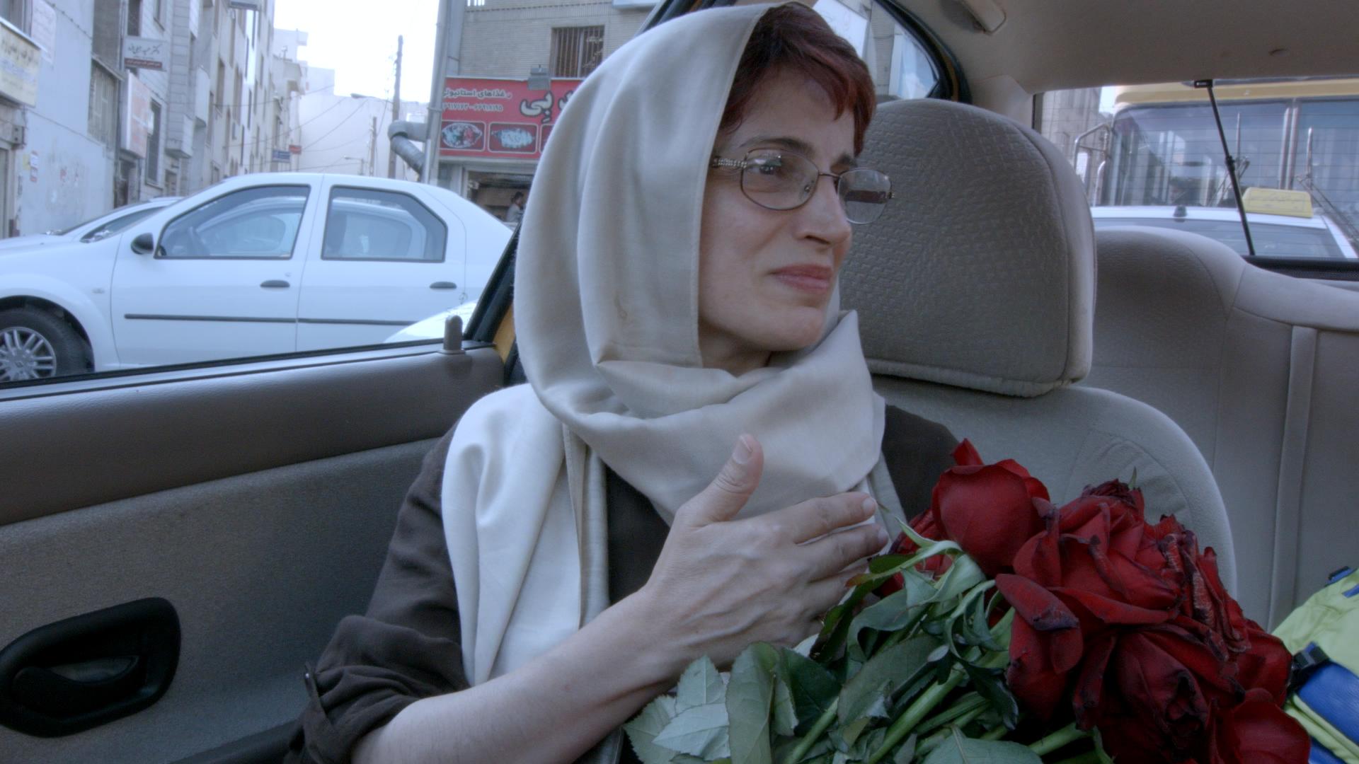 Nasrin Sotoudeh sits in a car holding a bouquet of roses