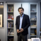 Osman Kavala stands in front of shelf with books and files in an office