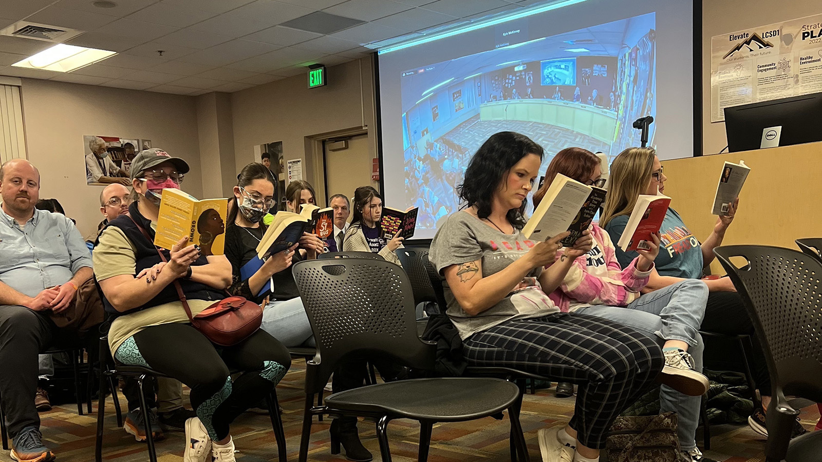Parents and students read banned books silently during a school board meeting.