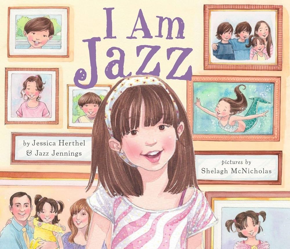 A book cover for I am Jazz by Jessica Herthel and Jazz Jennings, illustrated by Shelagh McNicholas. The illustration features a young girl in a pink striped shirt is smiling in front of a collection of photos on the wall.