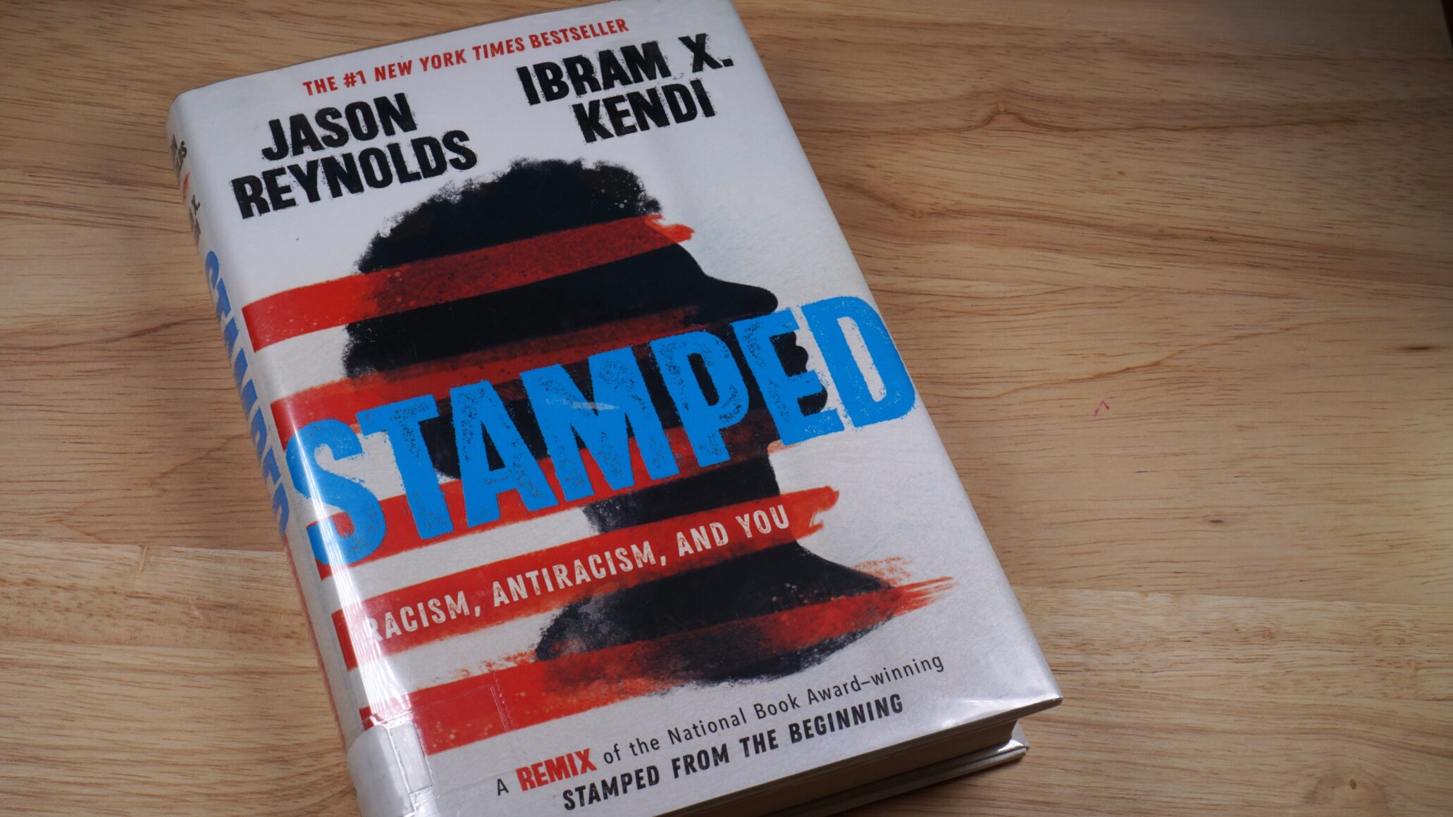 The book Stamped by Jason Reynolds and Ibram X. Kendi sits on a table.