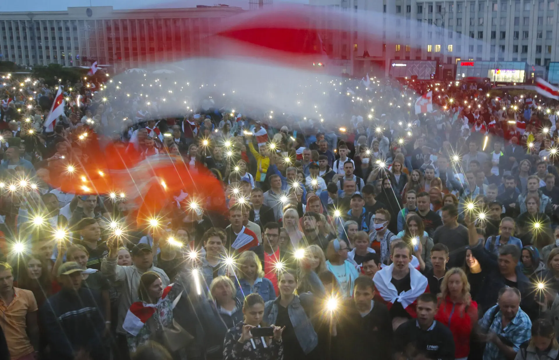 Belarusian opposition supporters activate the lights on their phones and wave old Belarusian national flags during a protest rally in front of the government building at Independent Square in Minsk, Belarus, Wednesday, Aug. 19, 2020. The authoritarian leader of Belarus complained that encouragement from abroad has fueled daily protests demanding his resignation as European Union leaders held an emergency summit Wednesday on the country’s contested presidential election and fierce crackdown on demonstrators.