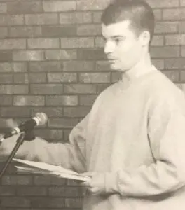 B. Batchelor reads his work in front of a microphone