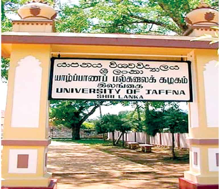 Entrance gate of the University of Jaffna in Sri Lanka, displaying the university name in Sinhala, Tamil, and English, with trees and a pathway visible in the background.