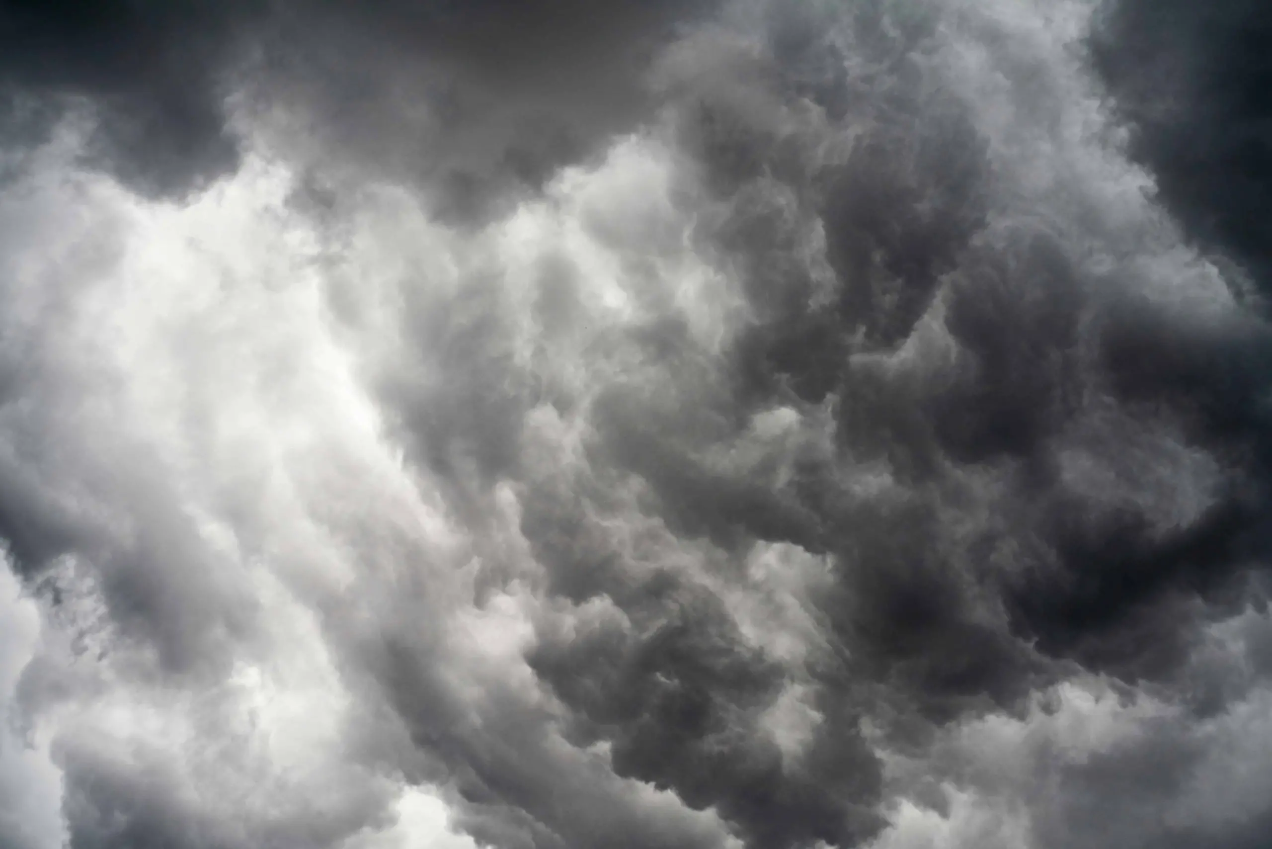 Dark, swirling storm clouds fill the sky, creating a dramatic and intense atmosphere with shades of gray and white.
