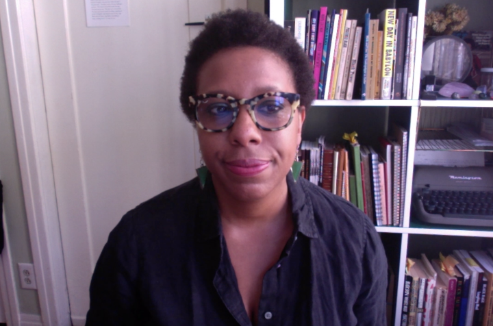 Poet and writer Morgan Parker sitting down in front of a bookshelf