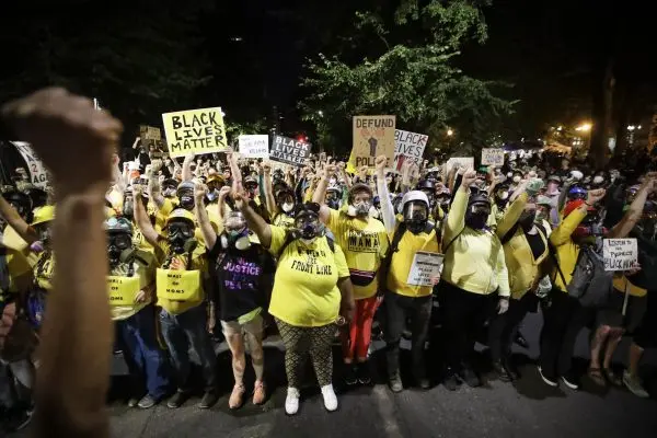 In this July 28, 2020, file photo, the “Wall of Moms” protest group marches with other demonstrators during a Black Lives Matter protest at a courthouse in Portland, Ore. 