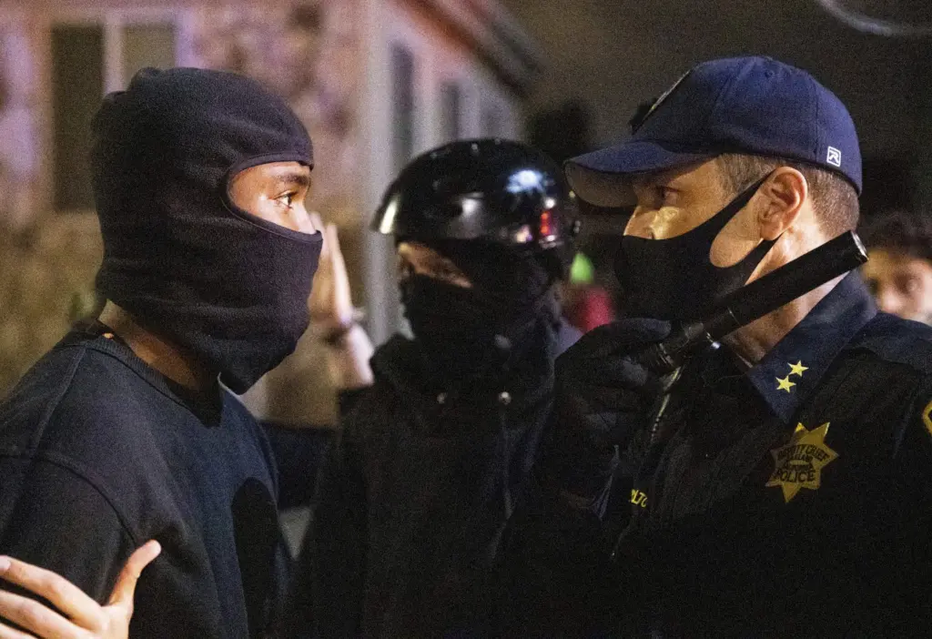 A demonstrator talks to Oakland police officers during a protest against police brutality in Oakland, Calif., on Friday, April 16, 2021.