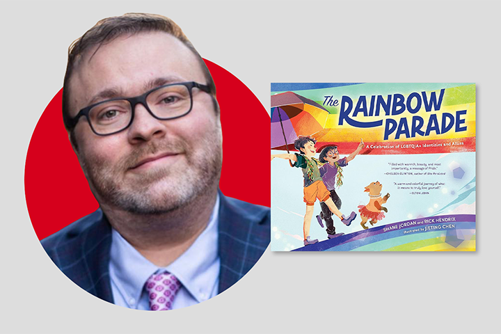 A person wearing glasses and a suit with a purple shirt and tie is next to a book cover titled The Rainbow Parade, featuring illustrated characters, a child, and a dog walking with a rainbow flag. The background is a red circle on a gray backdrop.