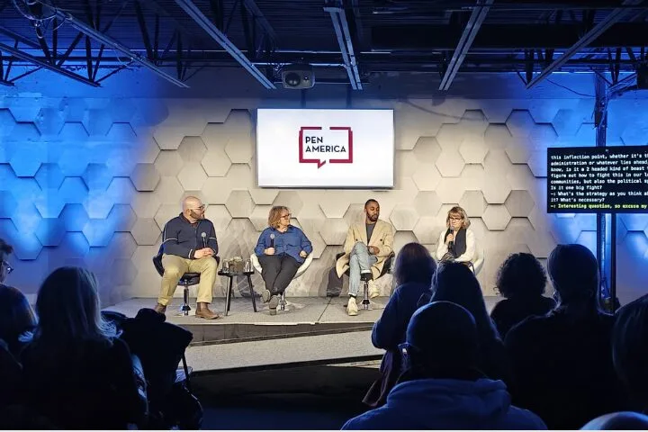 A panel of four people sits on stage under a Pen America sign. The background features a hexagonal pattern with blue lighting. An audience watches, and a screen displays text.