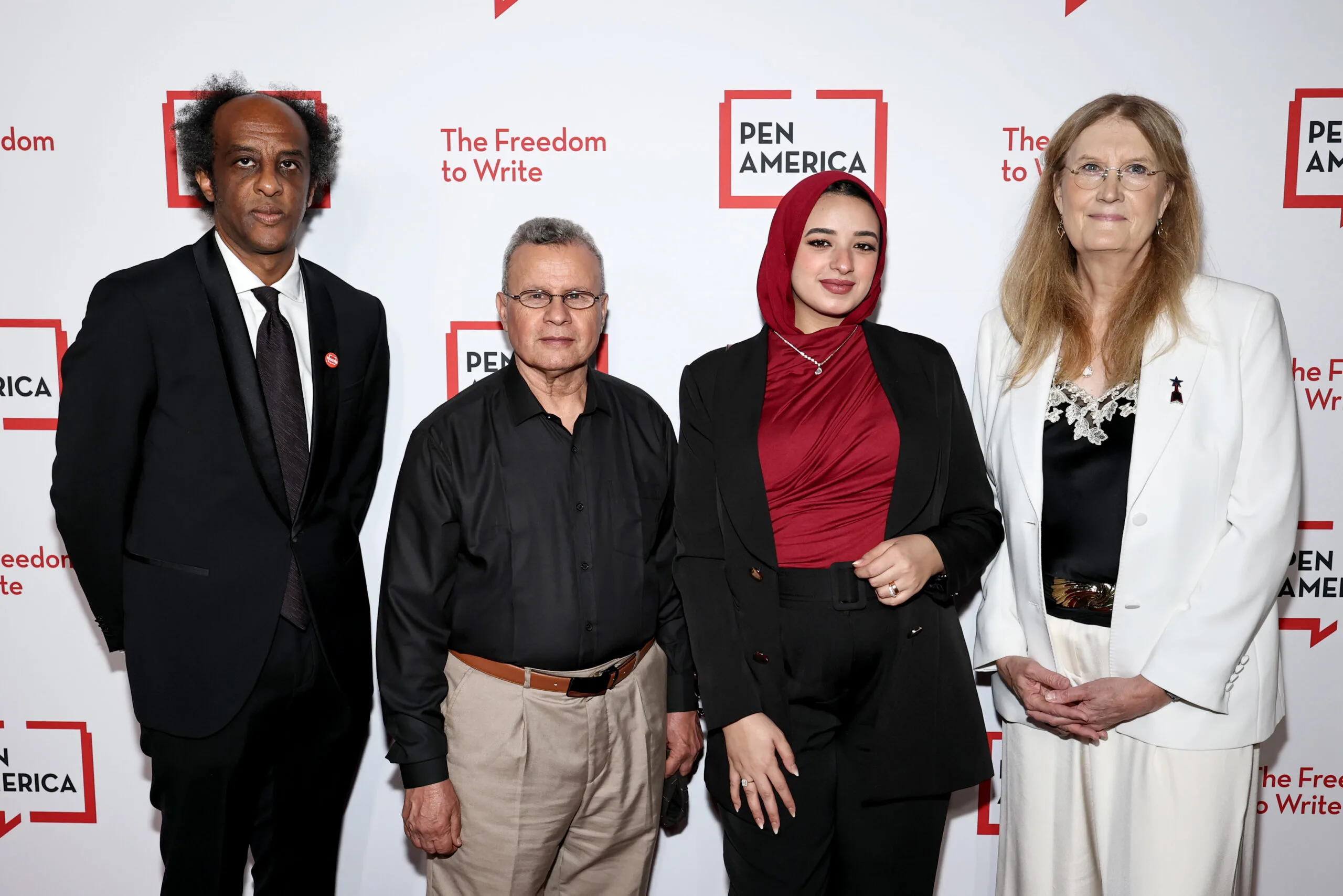 Four people stand together in formal attire at a PEN America event, with a backdrop reading “The Freedom to Write” and “PEN America” in red and black text.