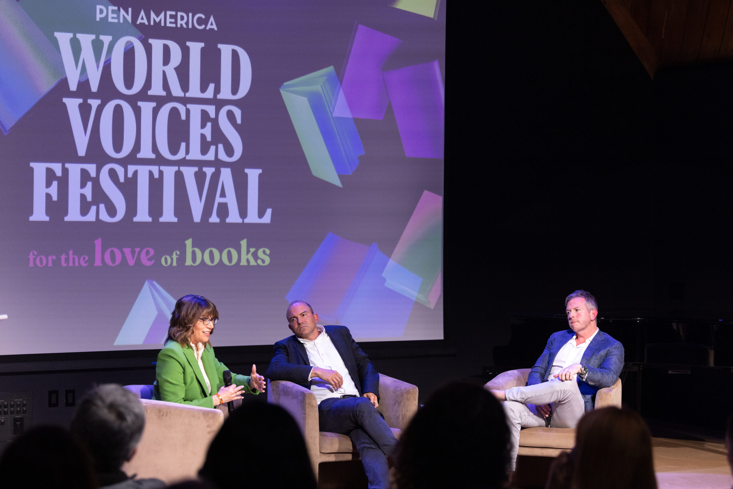 Three people sit on stage in armchairs having a discussion at the PEN America World Voices Festival, in front of a large screen reading for the love of books. An audience is visible in the foreground.