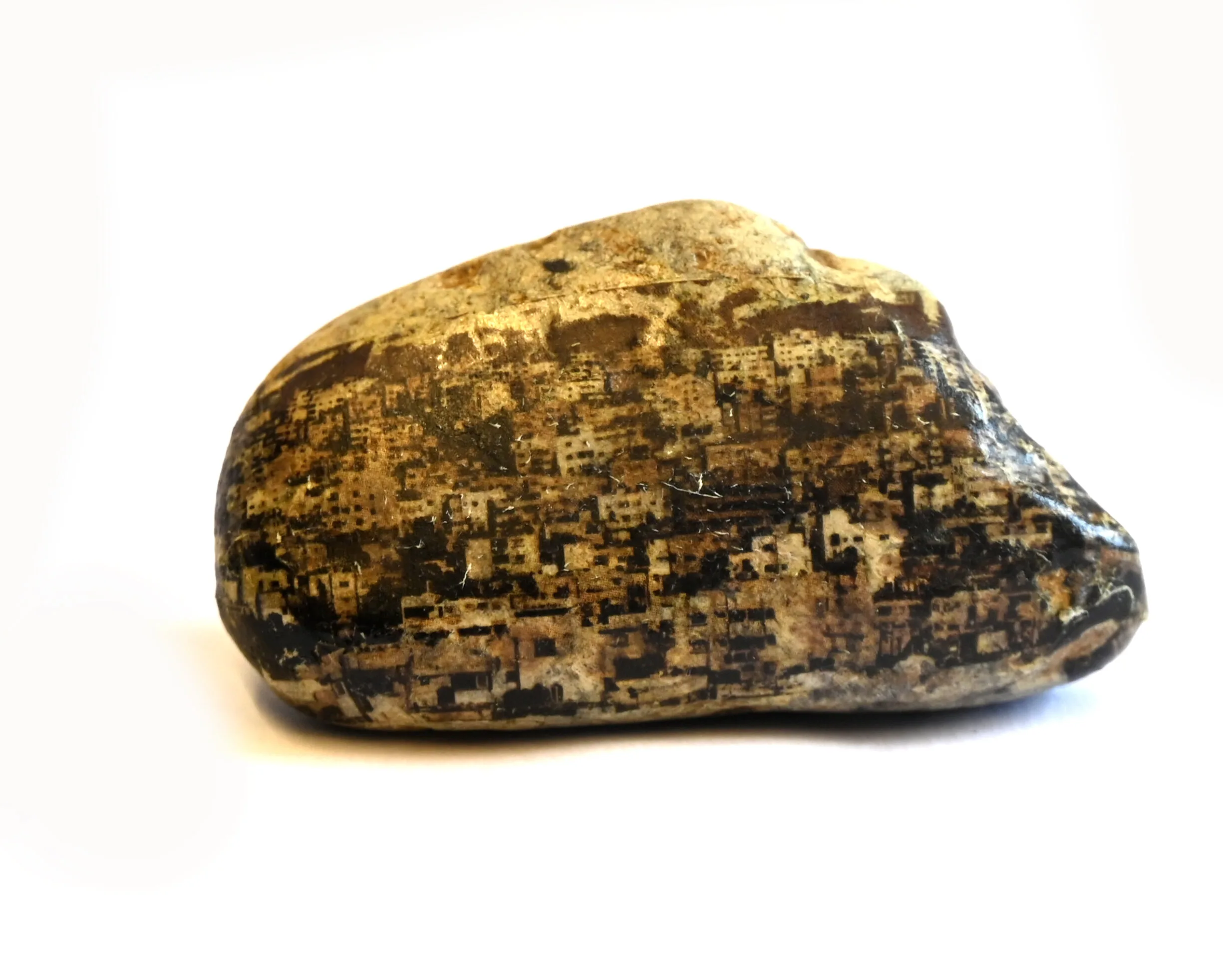 A smooth, oval-shaped stone with a cityscape image printed on its surface, showing numerous buildings. The stone is placed against a plain white background.