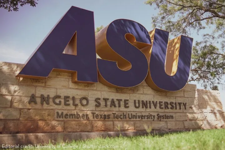 Large block letters ASU sit atop a stone sign that reads Angelo State University, Member, Texas Tech University System, surrounded by trees and sunlight.