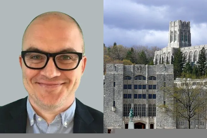 A man with glasses and a suit smiles at the camera on the left; on the right is a large stone building with a statue and a tall tower, surrounded by trees.